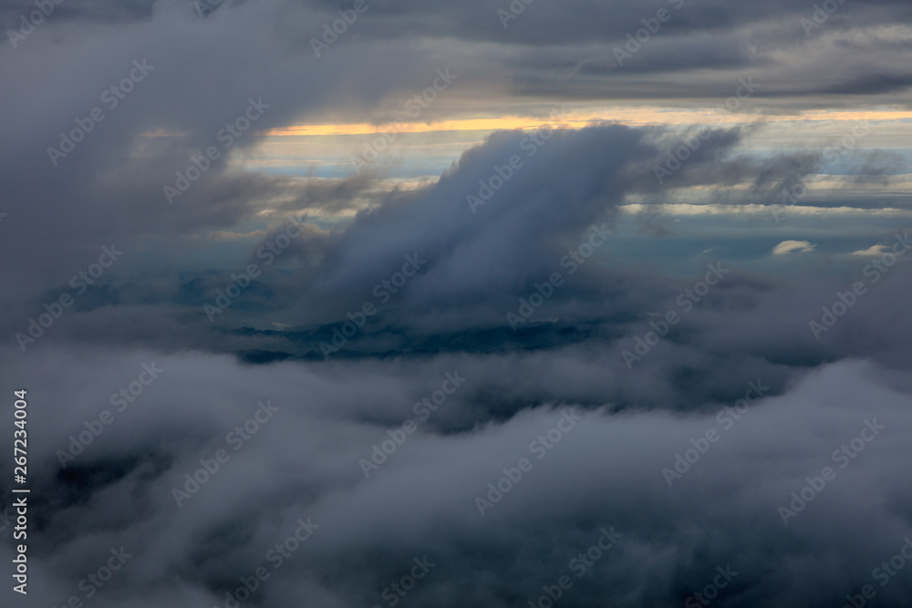 Abstract photograph above the clouds, sea of clouds effect, flying through the sky, aerial view, white puffy clouds and blue sky. Low pressure front atmospheric effect, cloudscape, cloudy weather