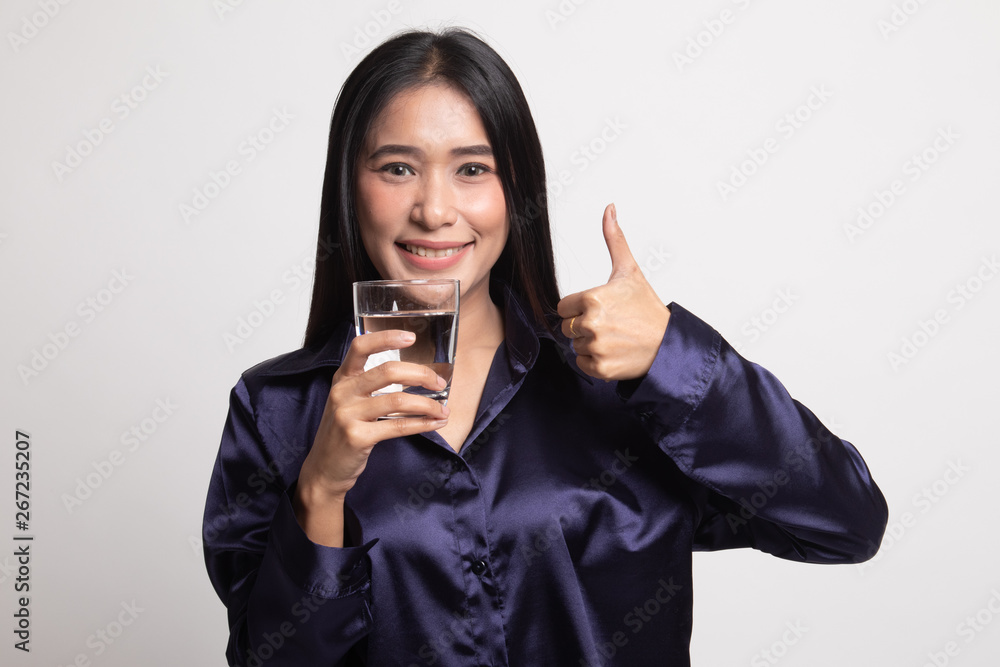 Young Asian woman thumbs up with a glass of drinking water. Young Asian woman thumbs up with a glass of drinking water.