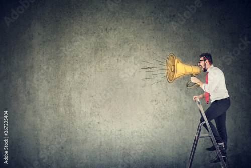 man standing on a ladder and screaming into a megaphone photo