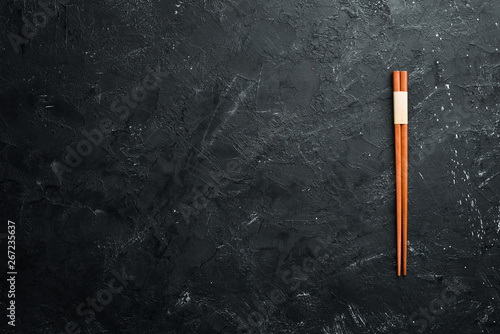 Fotografie Wooden chopsticks on a black stone background