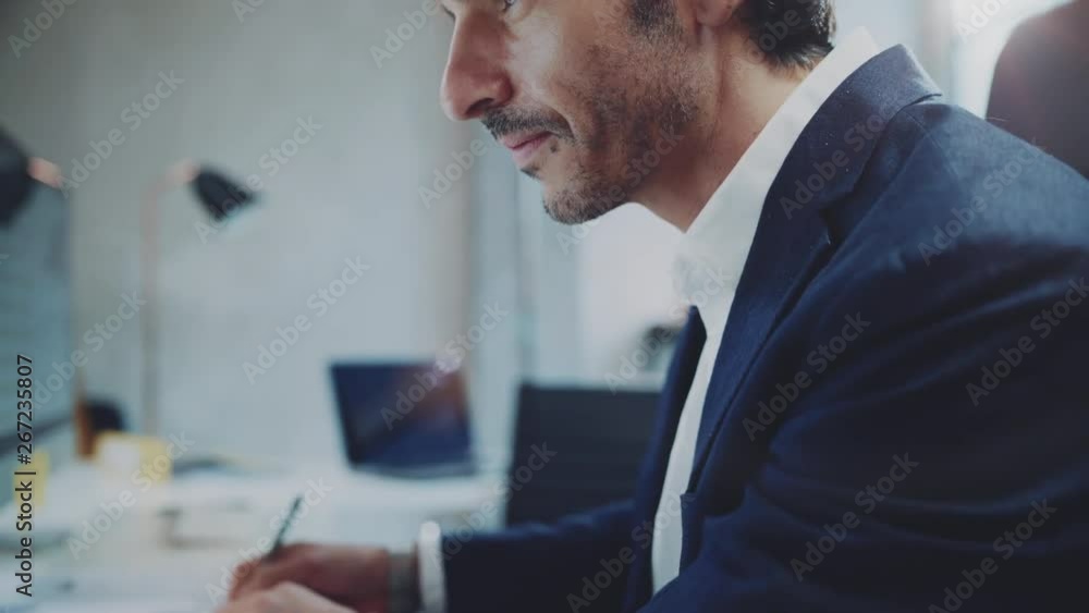 Businessman working at sunny office on desktop computer while sitting at the table.Blurred background. Businessman working at sunny office on desktop computer while sitting at the table.Blurred background.