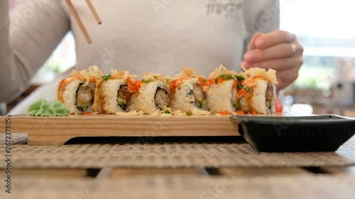 Woman eatinf sushi rolls in japanese restaurant, close up photo