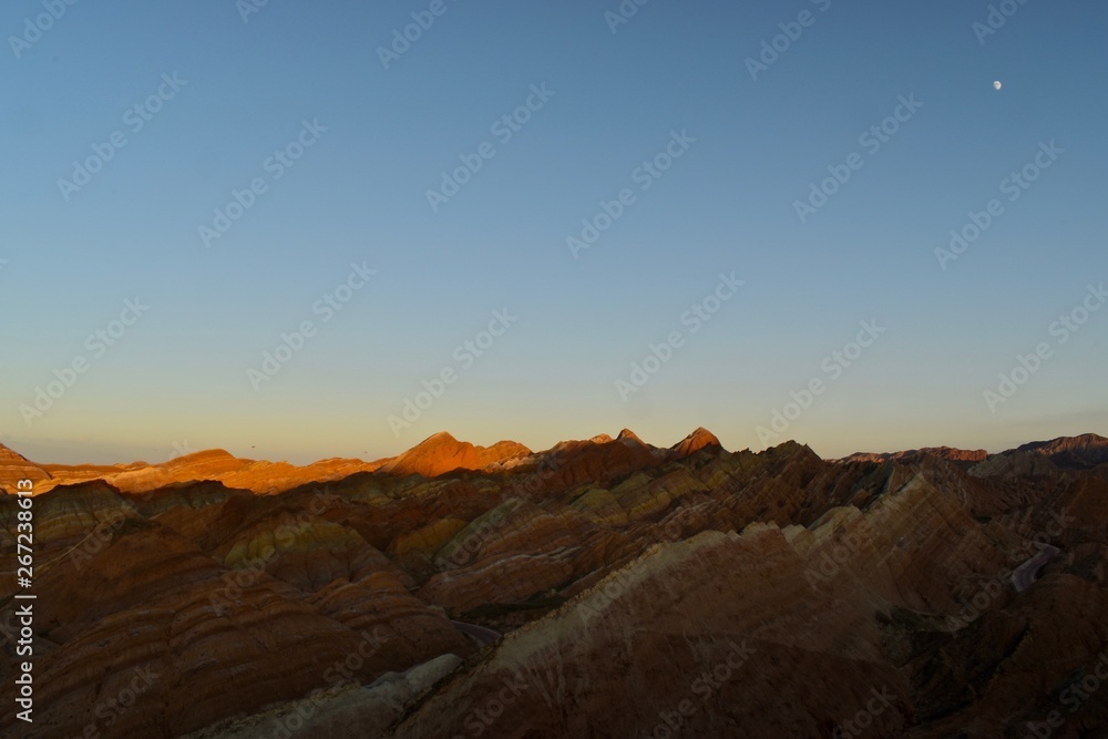 Small moon and colorful hills known as Rainbow mountains of China during sunset in Zhangye Danxia Landform Geological Park, Gansu province, China