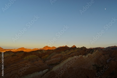 Small moon and colorful hills known as Rainbow mountains of China during sunset in Zhangye Danxia Landform Geological Park, Gansu province, China © PhotoZeli