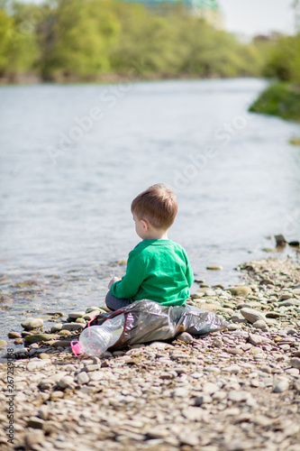 Save environment concept, a little boy collecting garbage and plastic bottles on the beach to dumped into the trash.