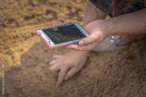 lady hold her mobile during pick rice seeds on the ground