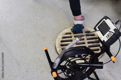 Sewer inspection camera. Man removing drainage grill on background.