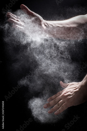 Moody, Shadowy High-Speed Photo of a Caucasian Man's Hands Clapping Together in an Explosion of Dust and Powder - with a Black Background