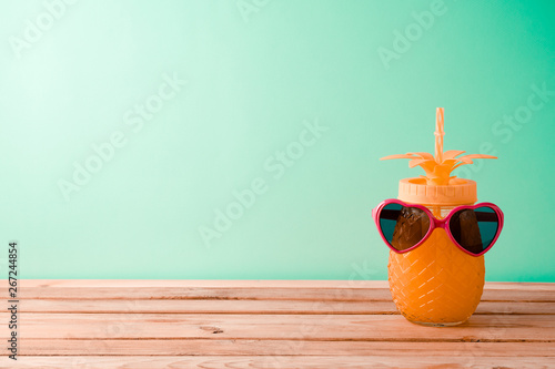 Summer vacation background with cute pineapple juice and sunglasses on wooden table