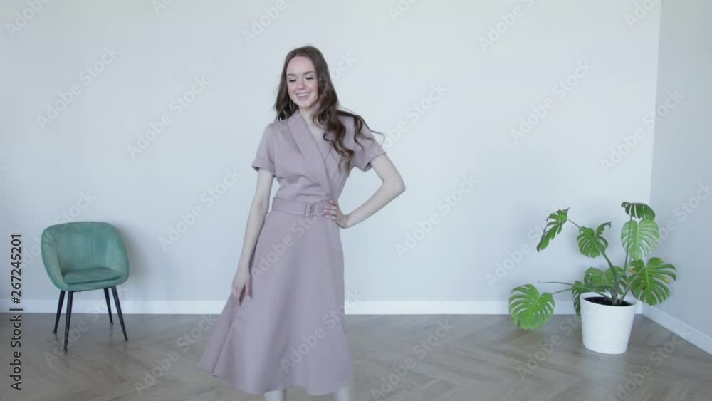 Attractive girl model posing smiling in gray dress.Slow motion Attractive girl model posing smiling in gray dress.Slow motion