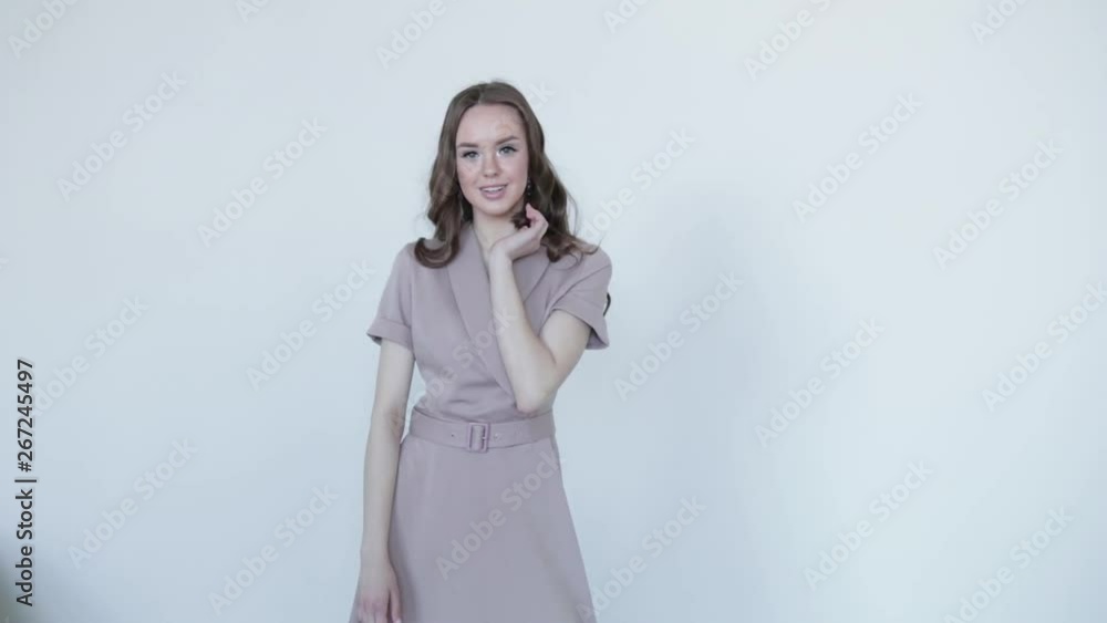 Attractive girl model posing smiling in grey dress on grey background .Slow motion Attractive girl model posing smiling in grey dress on grey background .Slow motion