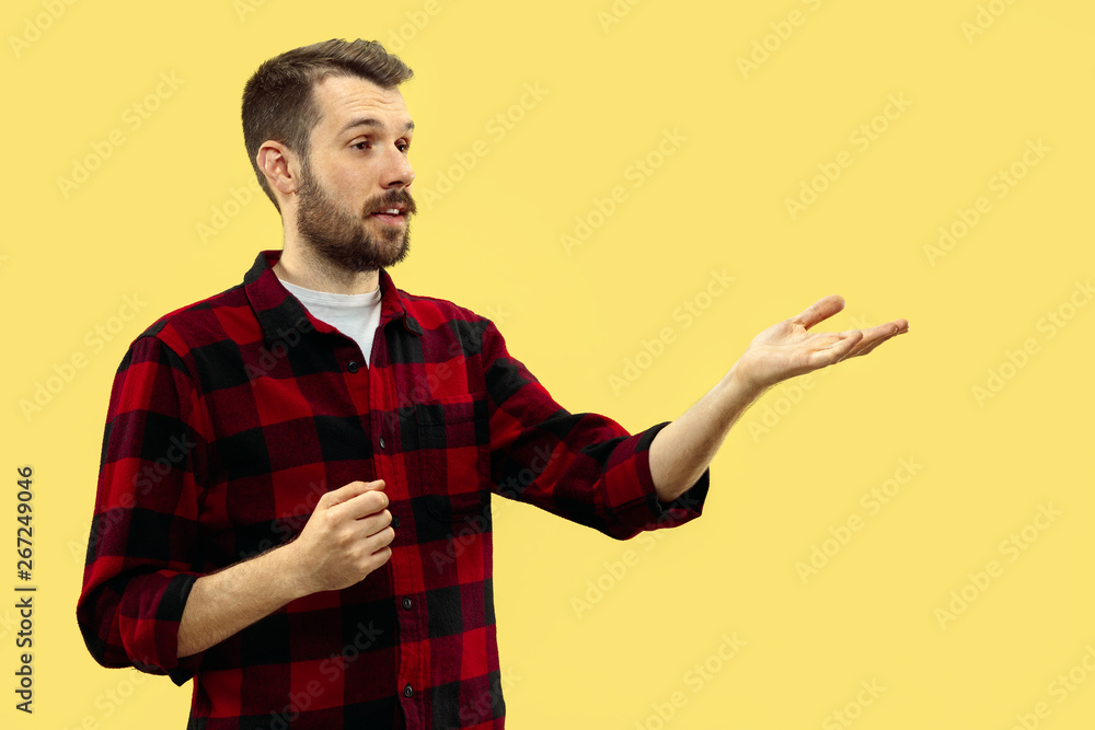 Half-length close up portrait of young man in shirt on yellow background. The human emotions, facial expression concept. Front view. Trendy colors. Negative space. Showing or pointing. Half-length close up portrait of young man in shirt on yellow background. The human emotions, facial expression concept. Front view. Trendy colors. Negative space. Showing or pointing.