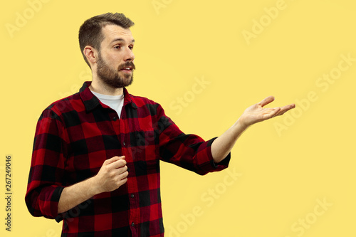 Half-length close up portrait of young man in shirt on yellow background. The human emotions, facial expression concept. Front view. Trendy colors. Negative space. Showing or pointing.