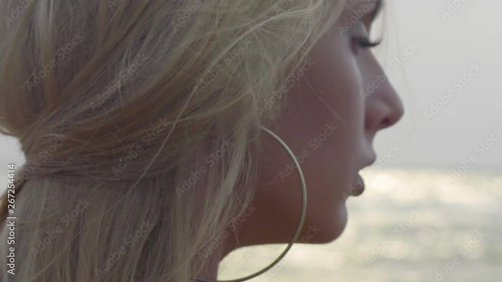 Extreme Close up of Beautiful blonde woman posing at the beach, with skin texture, in the afternoon, with sea blurred background. 4K slow motion. Extreme Close up of Beautiful blonde woman posing at the beach, with skin texture, in the afternoon, with sea blurred background. 4K slow motion.