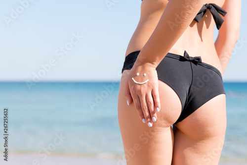 Pretty woman has made of sunblock on her ass at the beach