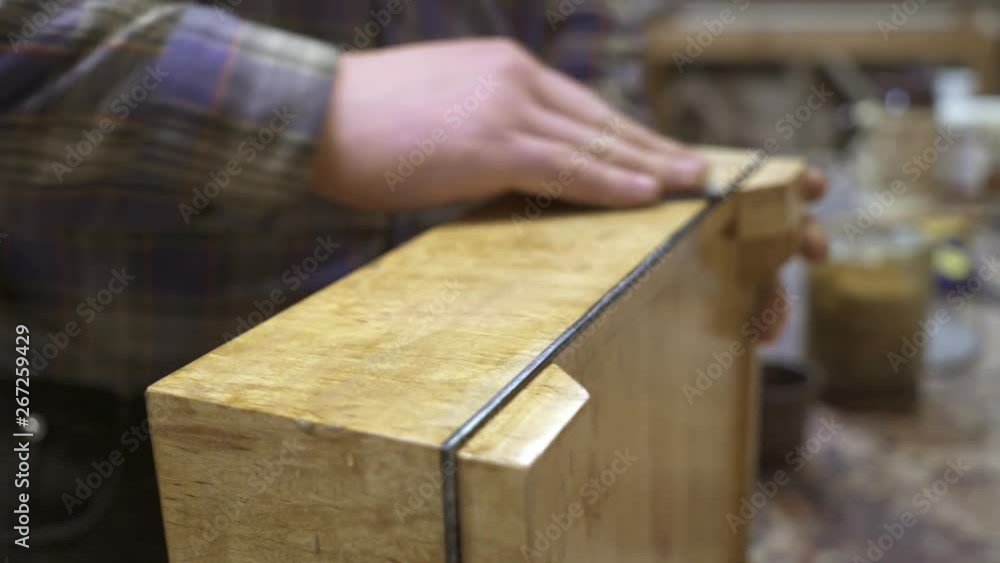 Right male hand cleaning a light wooden surface of stand with a rag. Handheld shot of male hand professionally cleaning an old light wooden box with circular motions Right male hand cleaning a light wooden surface of stand with a rag. Handheld shot of male hand professionally cleaning an old light wooden box with circular motions