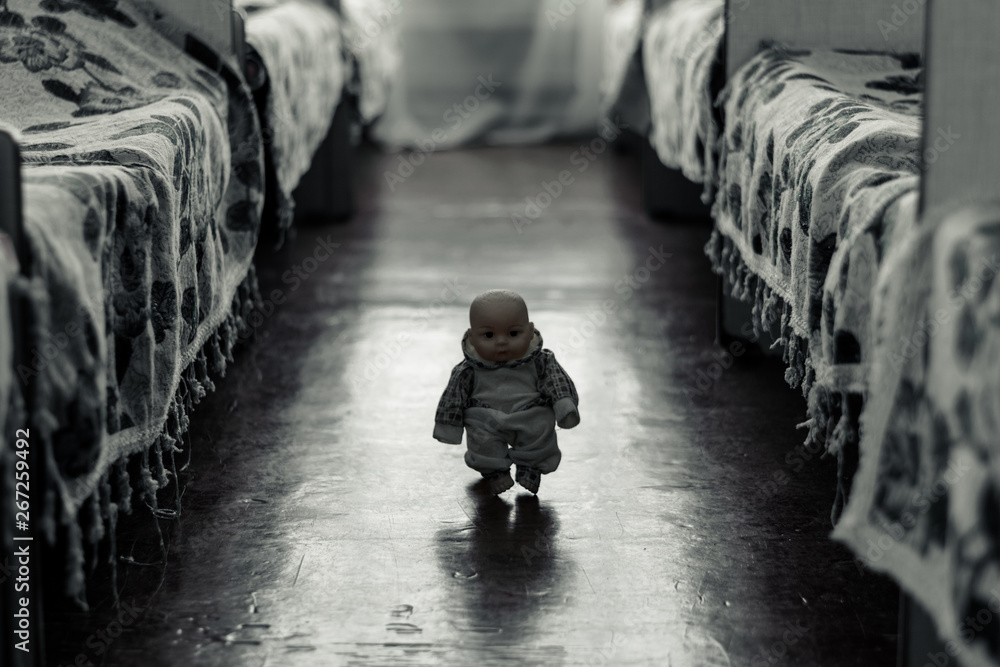 Little scary doll walks between the beds - obrazy, fototapety, plakaty 