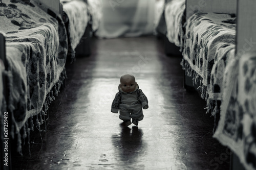 Little scary doll walks between the beds photo