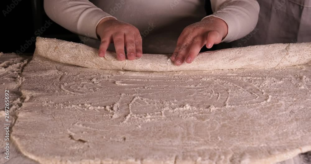 A little boy on a black background helps his father (dad) chef, preparing the dough to roll out for the pizza buns bread cakes and various flour products. Concept of: Little Chef, Baker, Slow motion. A little boy on a black background helps his father (dad) chef, preparing the dough to roll out for the pizza buns bread cakes and various flour products. Concept of: Little Chef, Baker, Slow motion.