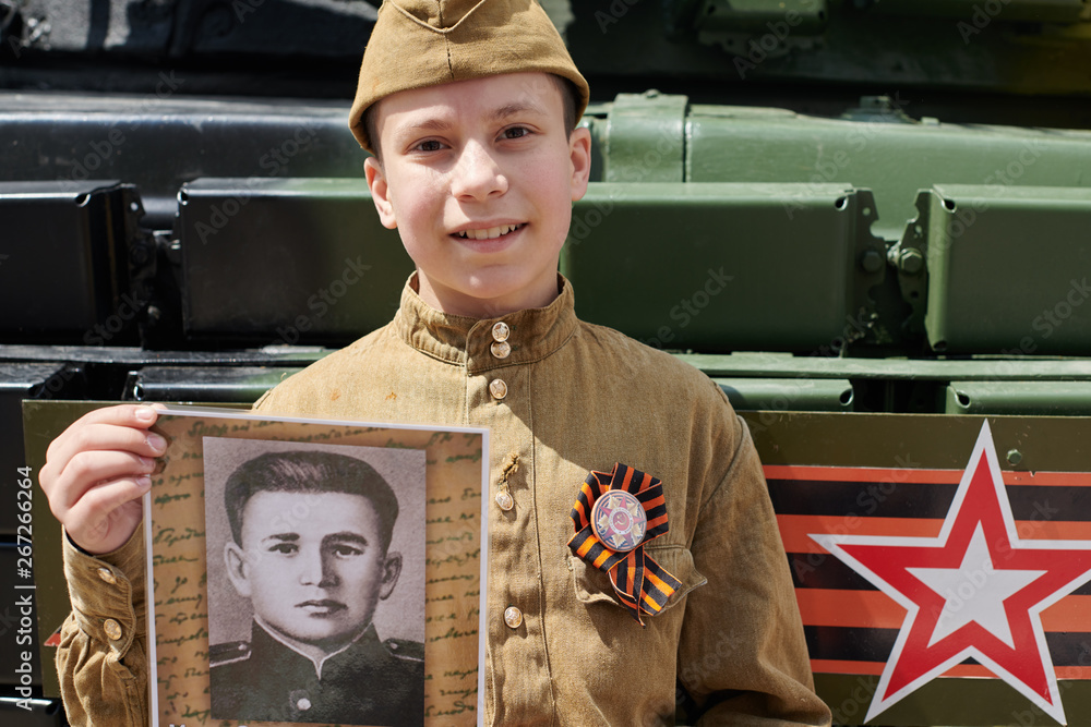 Boy dressed in Soviet military uniform during the second world war posing  near army tank and holds portrait his grandfather who fought and was a war  hero Stock Photo | Adobe Stock