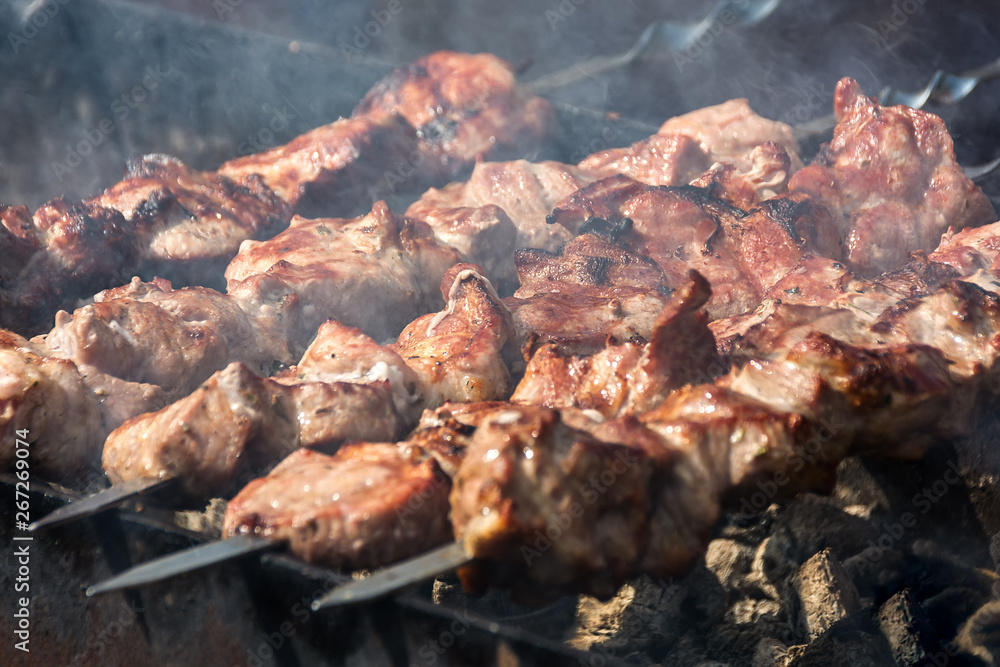 Shish kebab grilled meat on skewers is fried on a brazier. Sunny summer day Shish kebab grilled meat on skewers is fried on a brazier. Sunny summer day