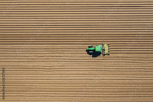 Aerial view of farming tractor plowing and spraying on field. Agriculture. View from above. Photo captured with drone.