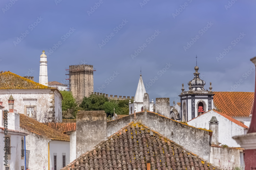 View of the fortress and Luso Roman castle of Óbidos, with buildings of Portuguese vernacular architecture and sky with clouds