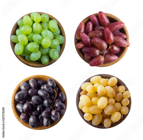 Grapes in a wooden bowl isolated on white background. Yellow, blue, pink and green grapes on white background. Vegetarian or healthy eating. Top view.