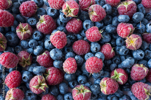 Ripe blueberries and raspberries. Mix berries and fruits. Top view. Background berries. Various fresh summer fruits. Pink and blue food. Fresh berries closeup. Background of fresh berries.