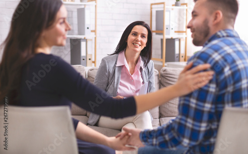 Smiling psychologist looking at lovely couple at therapy