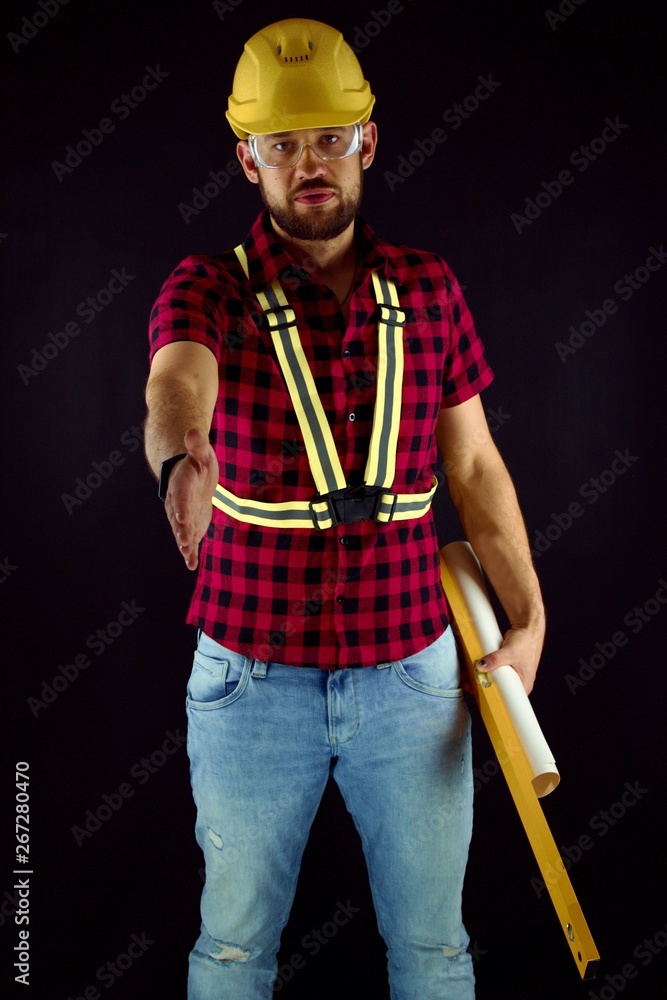 Construction Worker on black background press the flesh.Construction worker with yellow crash helmet. Builder on black baground. His arm is outstretched. Construction Worker on black background press the flesh.Construction worker with yellow crash helmet. Builder on black baground. His arm is outstretched.