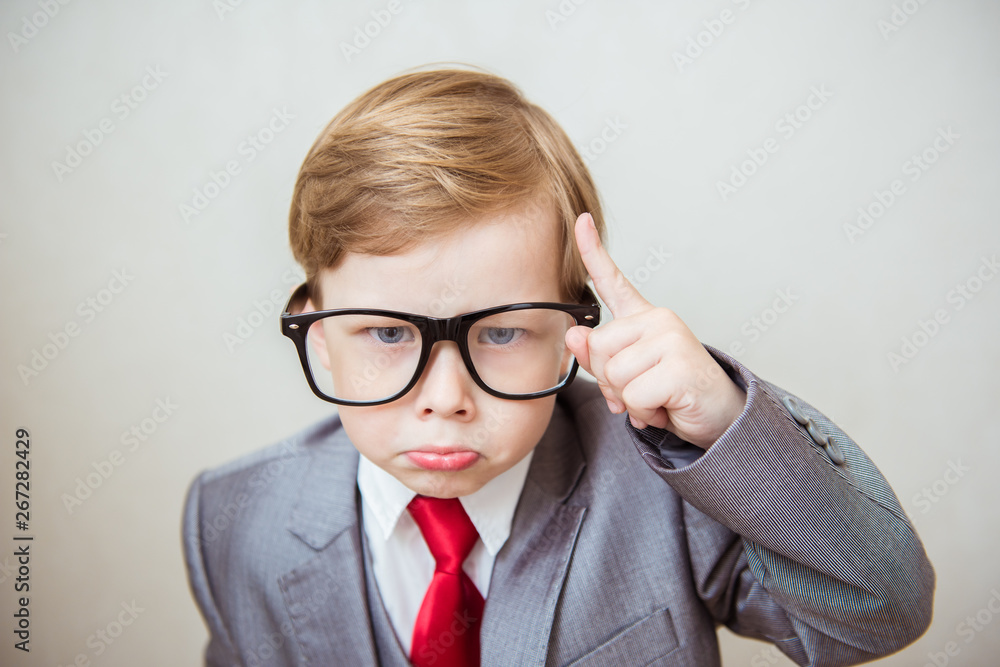 Serious boy standing with a finger in big glasses. Business, management and evil boss concept