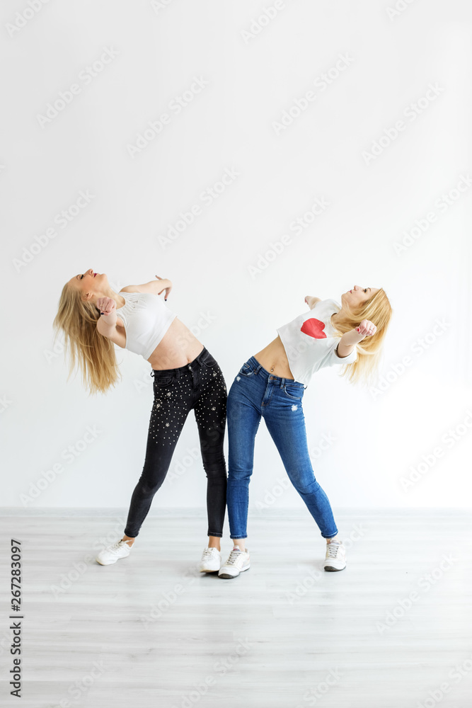 Two adult girls dancing in jeans and sneakers. The concept of sport, dance  and lifestyle Stock Photo | Adobe Stock
