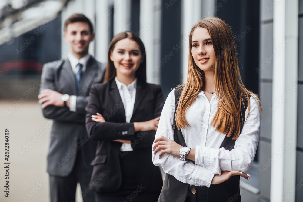 Business woman sitting i with crossed arms , looking at camera, smiling, two business people in background. Your future at your hands! Business woman sitting i with crossed arms , looking at camera, smiling, two business people in background. Your future at your hands!