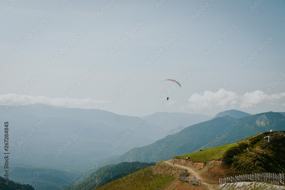 Paraglider silhouette flying over misty mountain valley in beautiful warm sunset colors - sport, active wallpapers full of freedom. Background with space for your montage Paraglider silhouette flying over misty mountain valley in beautiful warm sunset colors - sport, active wallpapers full of freedom. Background with space for your montage