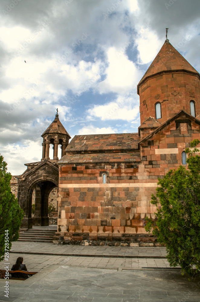 Side view on the Church of the blessed virgin with a bell tower in the Park among the trees in the fortress of Khor Virap against the spring sky covered with rain clouds