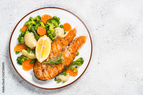 Canvas Print Grilled salmon fish steak with vegetables on white.