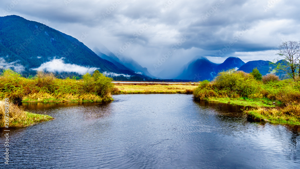 Dark rain clouds on a cold spring day at over the Pitt River and the surrounding mountains of the Coast Mountain Range near the town of Maple Ridge in British Columbia, Canada 