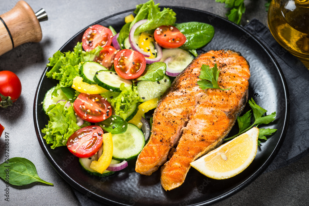 Grilled salmon fish steak with vegetables on black. Grilled salmon fish steak with vegetables on black.