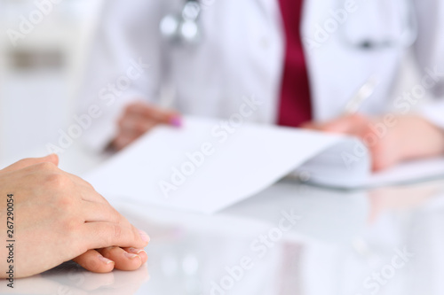 Unknown doctor woman consulting patient while filling up an application form at the desk in hospital. Just hands close-up. Medicine and health care concept © rogerphoto