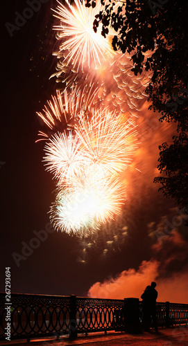 Fireworks over the river and a couple in love on the river bank