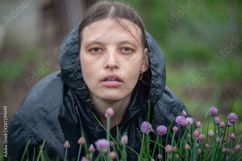 Portrait of happy girl in black jacket with hood against background of bright spring foliage in sunlight. Natural light effect lens. Selective focus, shallow depth of field. Art image of nature, bokeh