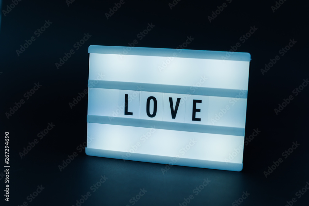 Photo of a light box with text, LOVE, over isolated dark background Photo of a light box with text, LOVE, over isolated dark background