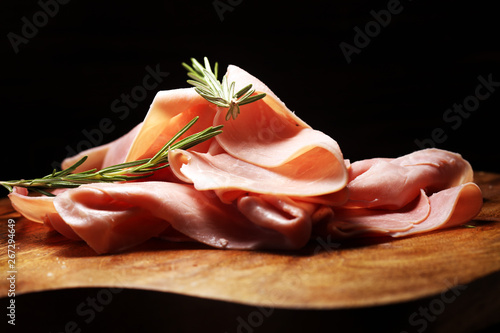 Sliced ham on wooden background. Fresh prosciutto cotto. Pork ham sliced with herbs