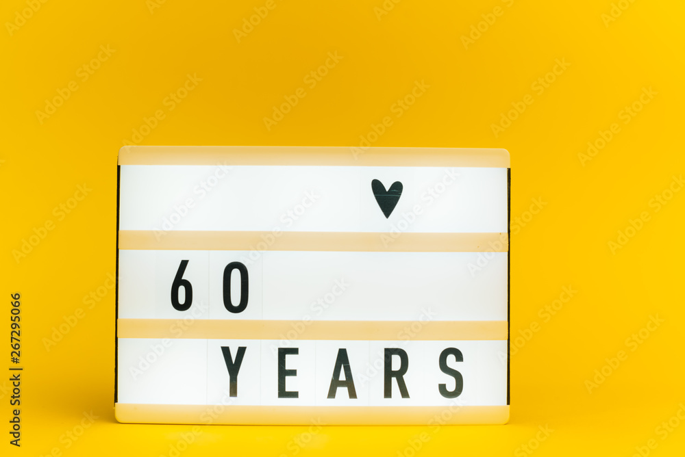 Photo of a light box with text, 60 YEARS, on isolated yellow background Photo of a light box with text, 60 YEARS, on isolated yellow background