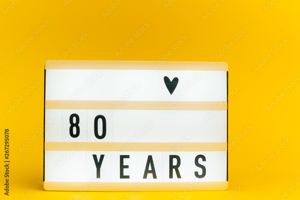 Photo of a light box with text, 80 YEARS, on isolated yellow background Photo of a light box with text, 80 YEARS, on isolated yellow background