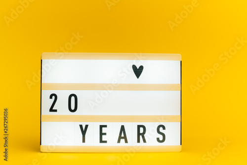 Photo of a light box with text, 20 YEARS, on isolated yellow background