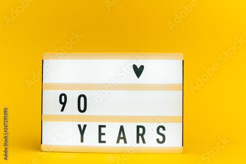 Photo of a light box with text, 90 YEARS, on isolated yellow background