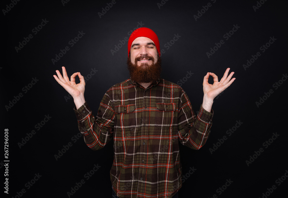 Bearded man taking deep breath peacefully meditating over dark background. Bearded man taking deep breath peacefully meditating over dark background.