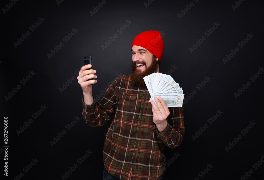 Photo of lucky smiling guy celebrating victory after making bets using gambling mobile application on his phone. Photo of lucky smiling guy celebrating victory after making bets using gambling mobile application on his phone.